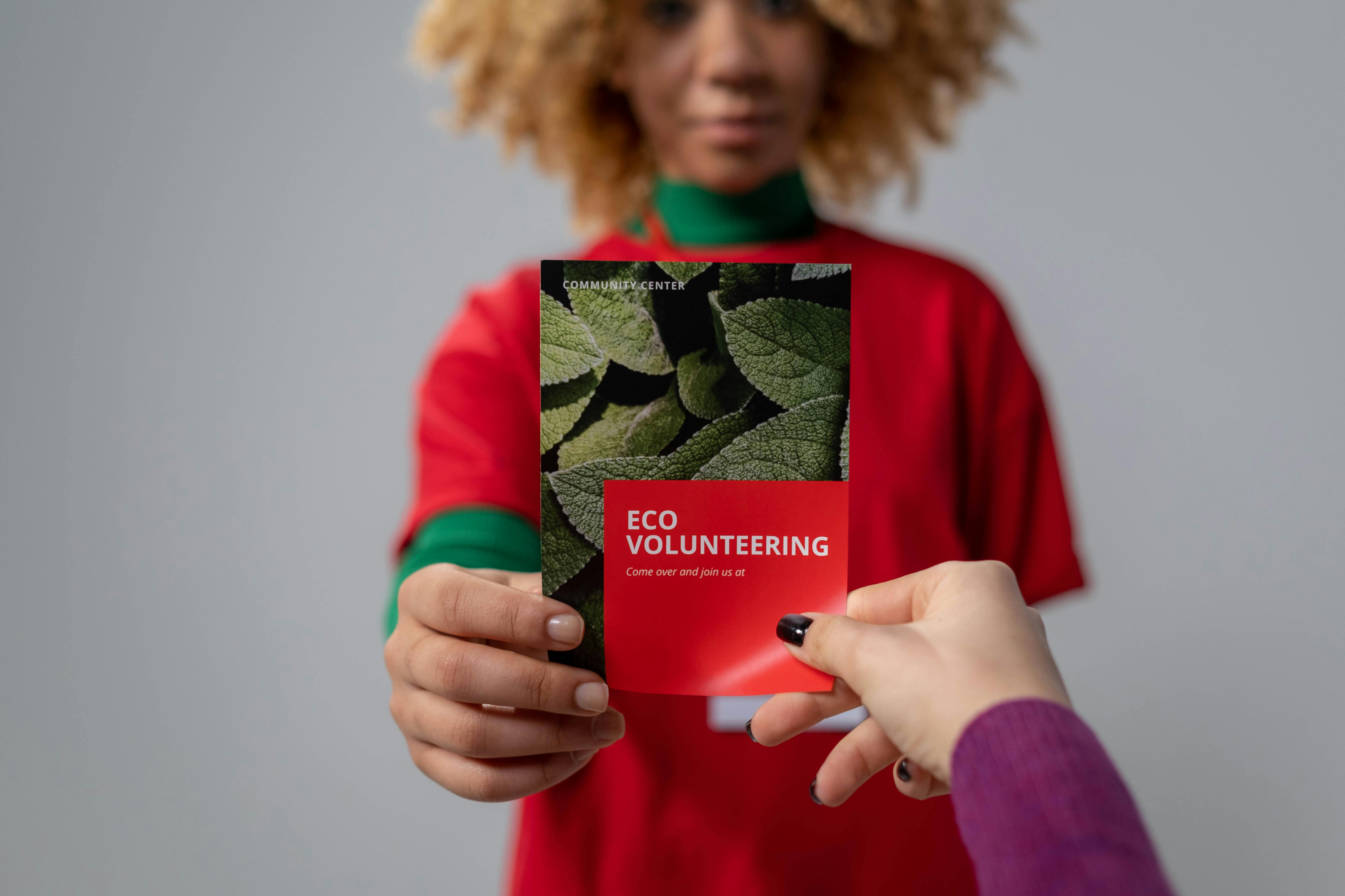 Close-up of hands exchanging an eco volunteering brochure, representing environmental awareness.